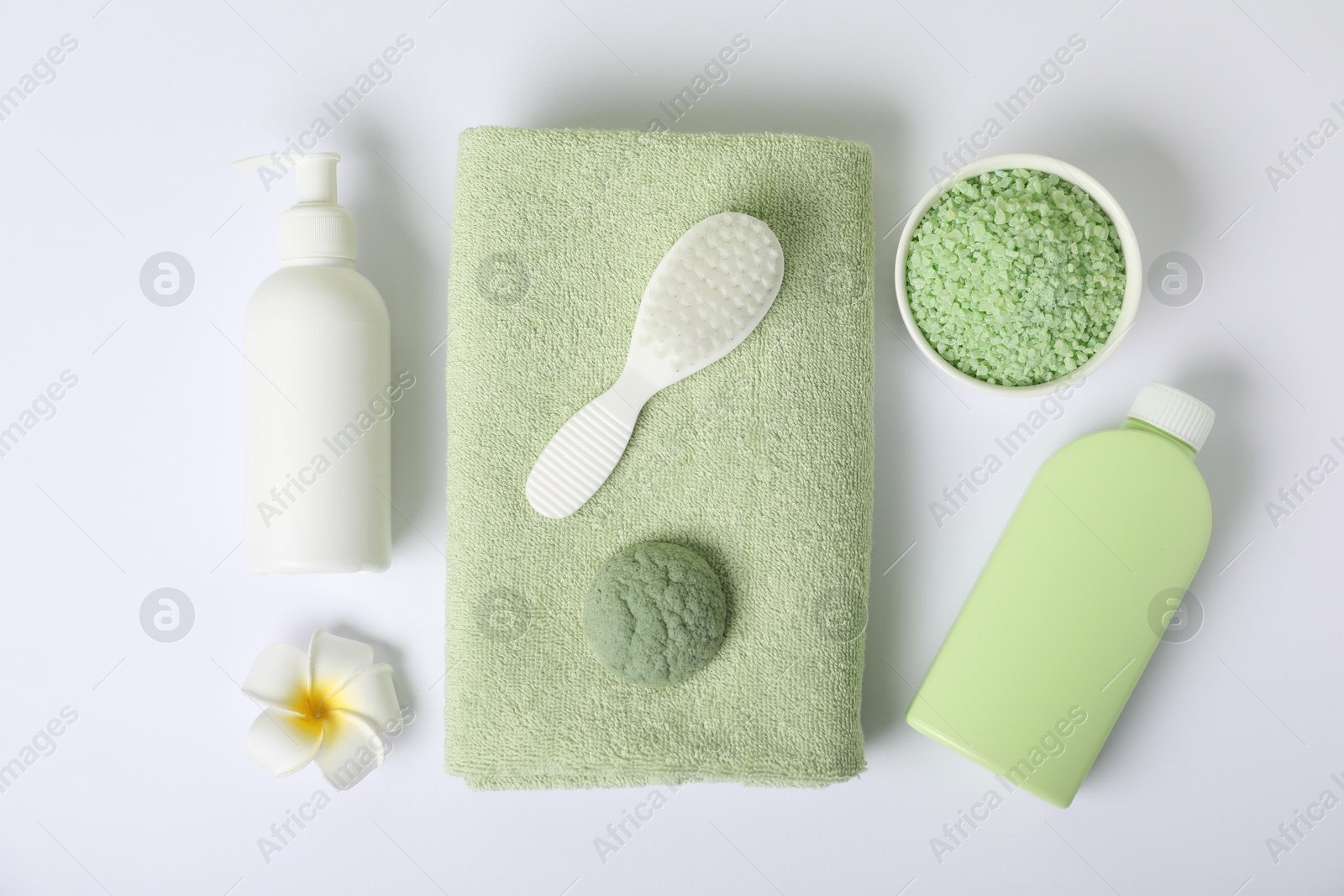 Photo of Fresh terry towel, cosmetic products, brush and plumeria flower on white background, flat lay