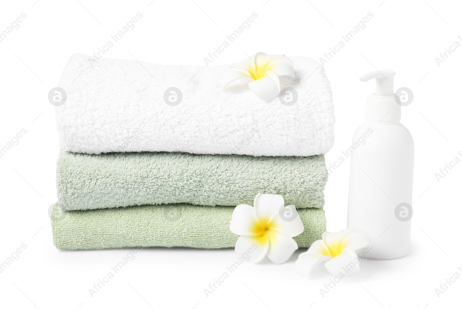 Photo of Stack of fresh terry towels, cosmetic product and plumeria flowers isolated on white