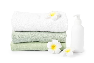 Photo of Stack of fresh terry towels, cosmetic product and plumeria flowers isolated on white