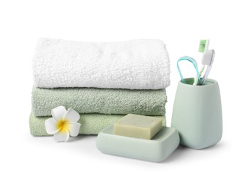 Photo of Stack of fresh terry towels, soap, toothbrushes and plumeria flower isolated on white