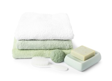 Photo of Stack of fresh terry towels, cosmetic products and brush isolated on white