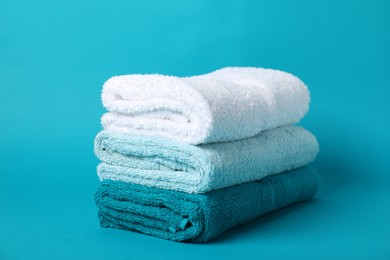 Photo of Stack of fresh terry towels on light blue background, closeup