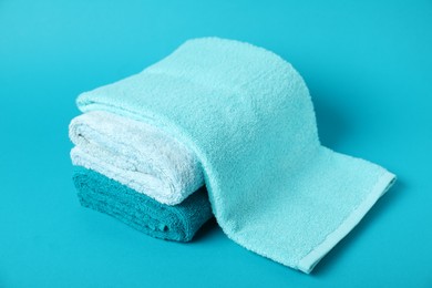 Photo of Stack of fresh terry towels on light blue background, closeup