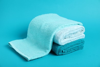 Photo of Stack of fresh terry towels on light blue background, closeup
