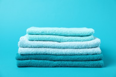 Photo of Stack of fresh terry towels on light blue background