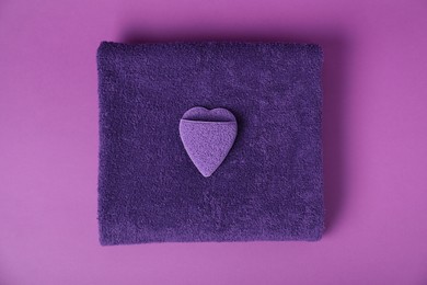 Photo of Fresh terry towel and sponge on purple background, top view