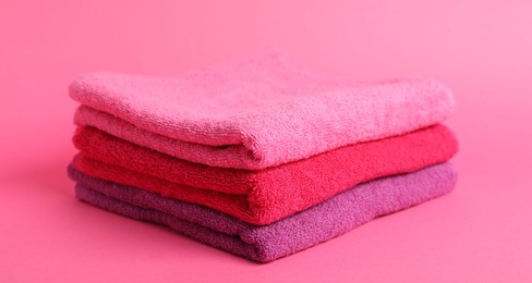 Photo of Stack of fresh terry towels on pink background, closeup