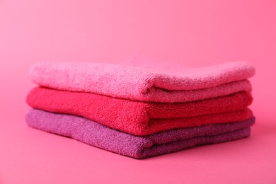 Photo of Stack of fresh terry towels on pink background, closeup