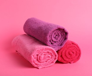Photo of Rolled fresh terry towels on pink background, closeup