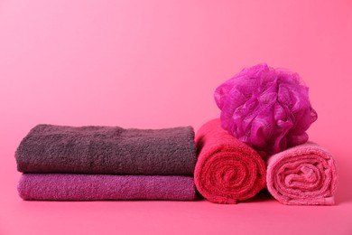 Photo of Fresh terry towels and sponge on pink background