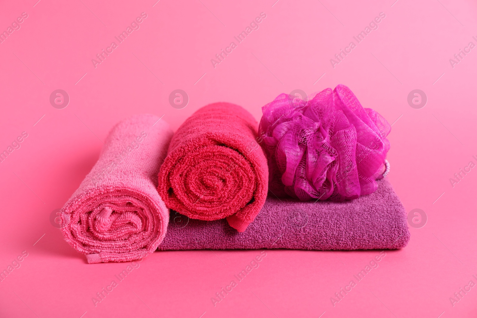 Photo of Fresh terry towels and sponge on pink background