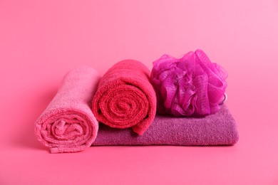 Photo of Fresh terry towels and sponge on pink background