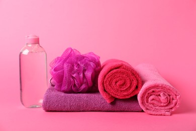 Photo of Fresh terry towels, cosmetic product and sponge on pink background