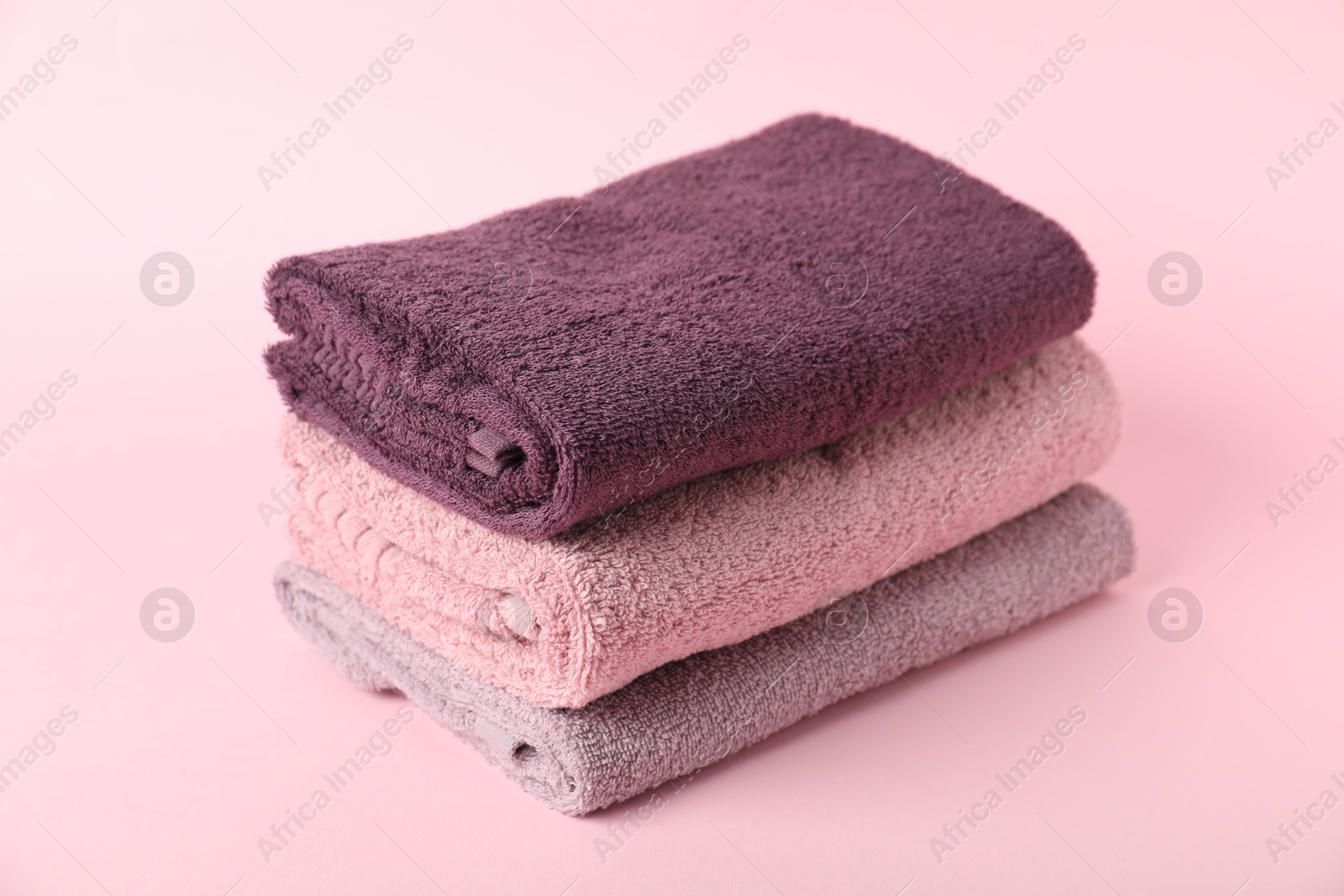 Photo of Stack of fresh terry towels on pink background, closeup