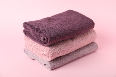 Photo of Stack of fresh terry towels on pink background, closeup