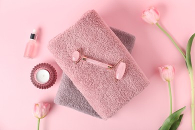 Photo of Fresh terry towels, candle, cosmetic product and tulip flowers on pink background, flat lay