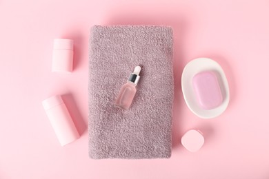 Photo of Fresh terry towels and cosmetic product on pink background, flat lay