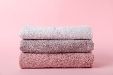 Photo of Stack of fresh terry towels on pink background