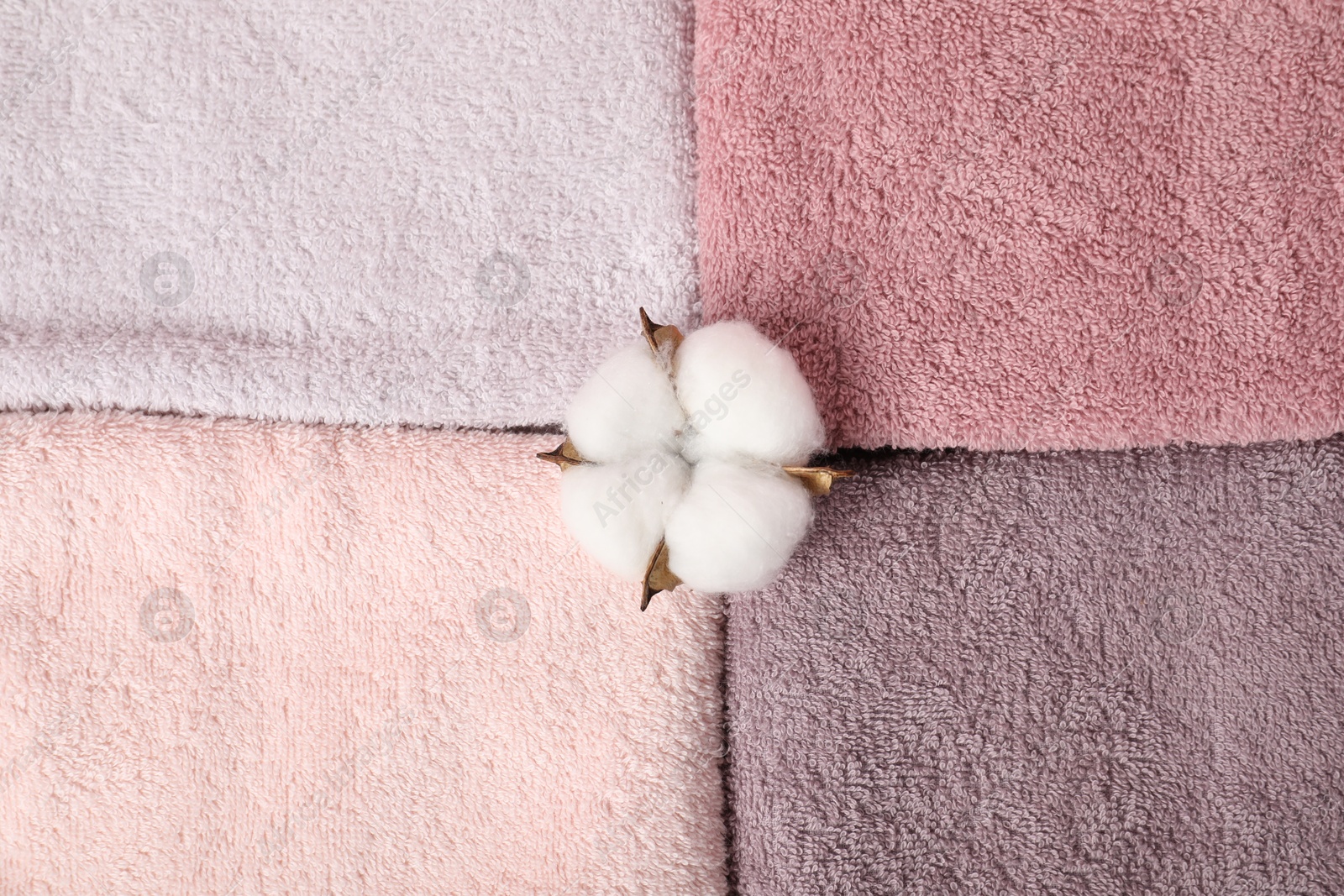 Photo of Fresh terry towels and plumeria flower as background, top view