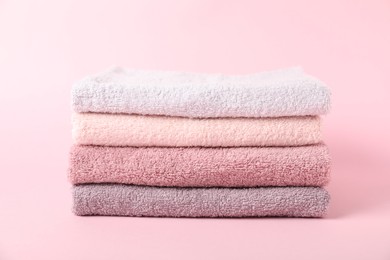 Photo of Stack of fresh terry towels on pink background