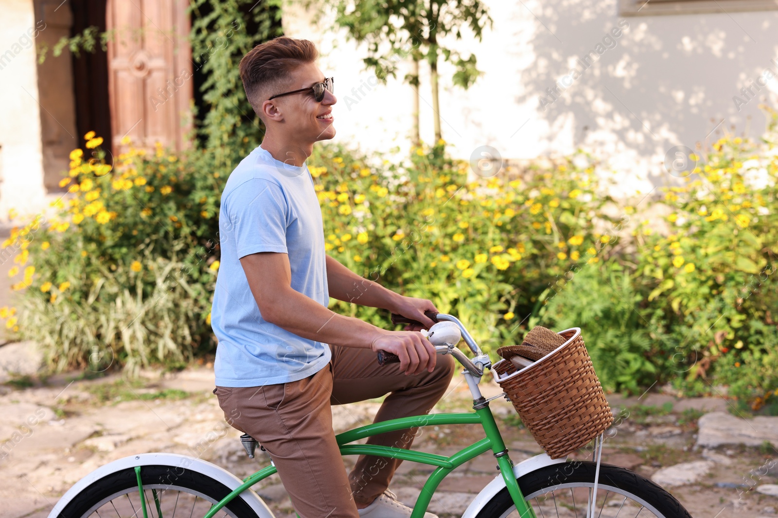 Photo of Happy man in sunglasses riding bicycle on city street
