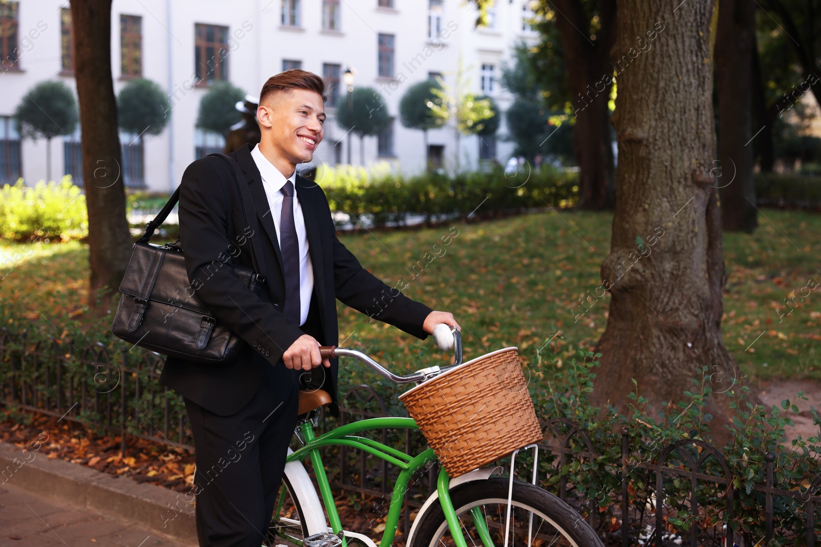 Photo of Man in suit riding bicycle on city street. Space for text