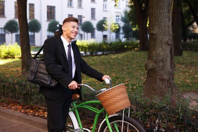 Photo of Man in suit riding bicycle on city street. Space for text