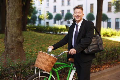 Photo of Man in suit riding bicycle on city street. Space for text