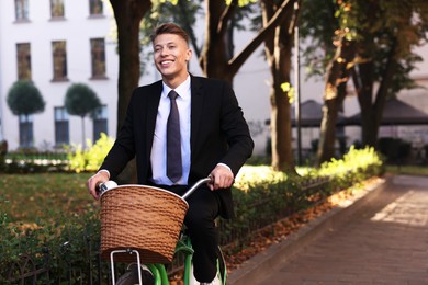 Photo of Man in suit riding bicycle on city street. Space for text