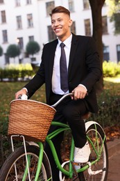 Photo of Man in suit riding bicycle on city street
