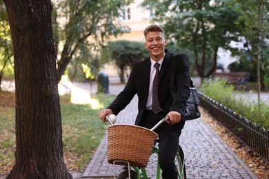 Photo of Man in suit riding bicycle on city street