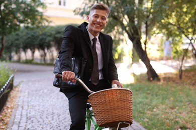 Photo of Man in suit riding bicycle on city street
