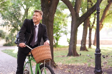 Photo of Man in suit riding bicycle on city street. Space for text