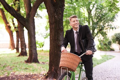 Photo of Man in suit riding bicycle on city street. Space for text