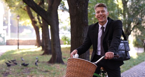 Photo of Man in suit riding bicycle on city street. Space for text