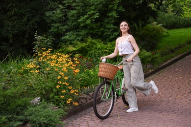 Photo of Happy woman walking bicycle in park. Space for text