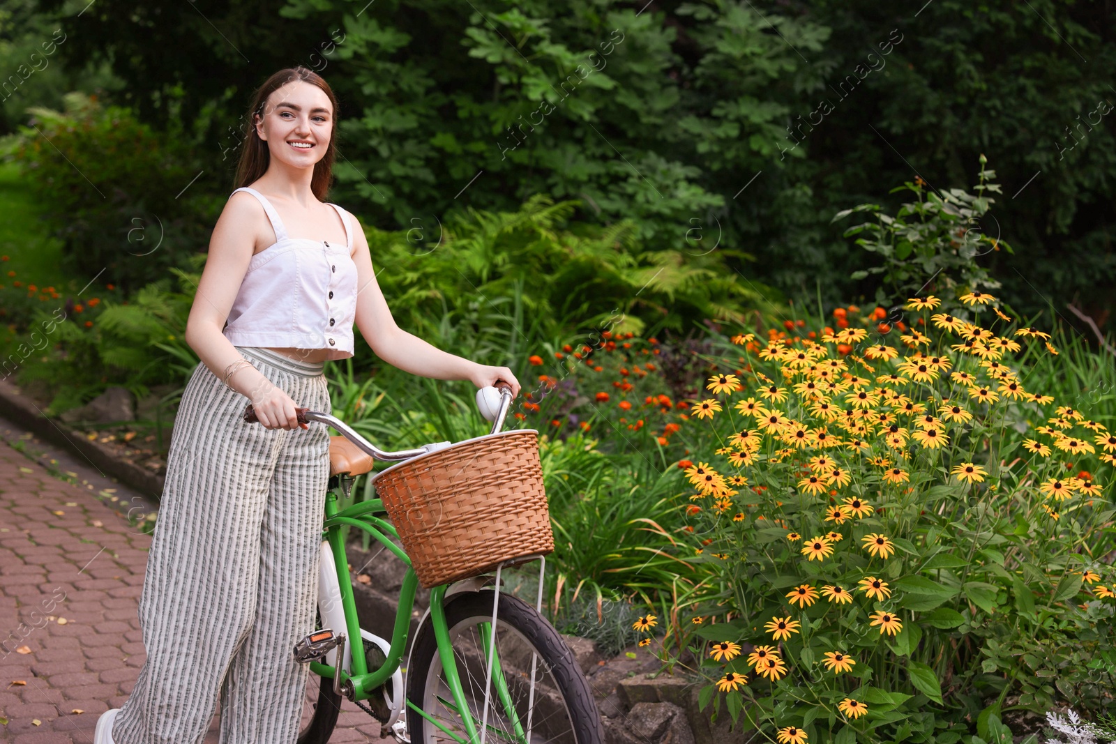 Photo of Happy woman walking bicycle in park. Space for text
