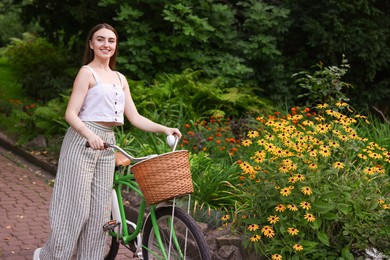 Photo of Happy woman walking bicycle in park. Space for text