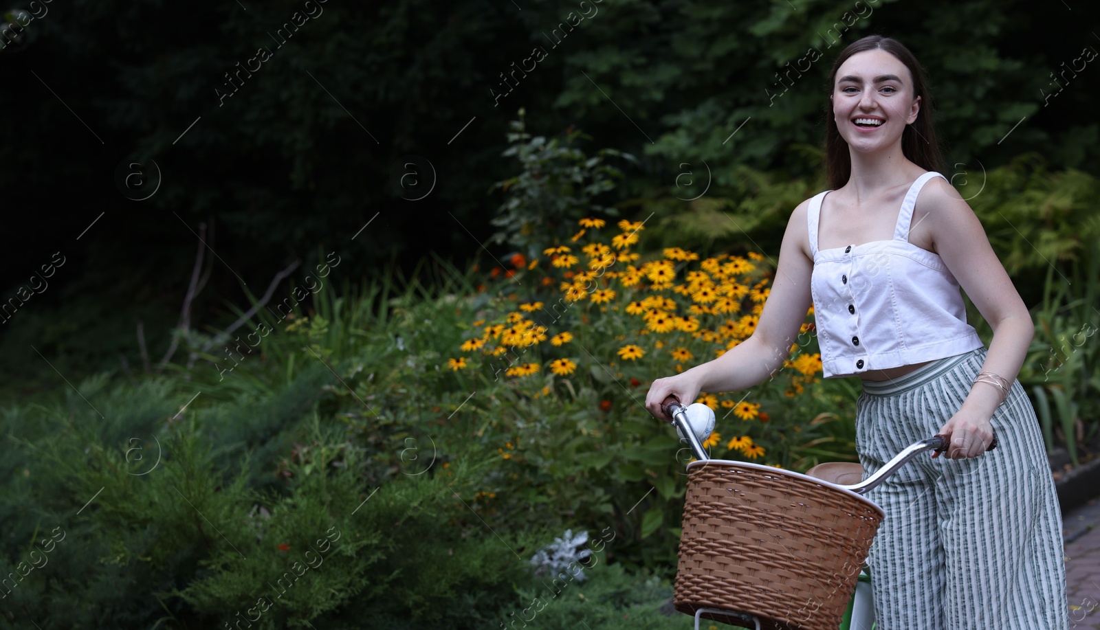 Photo of Happy woman walking bicycle in park. Space for text