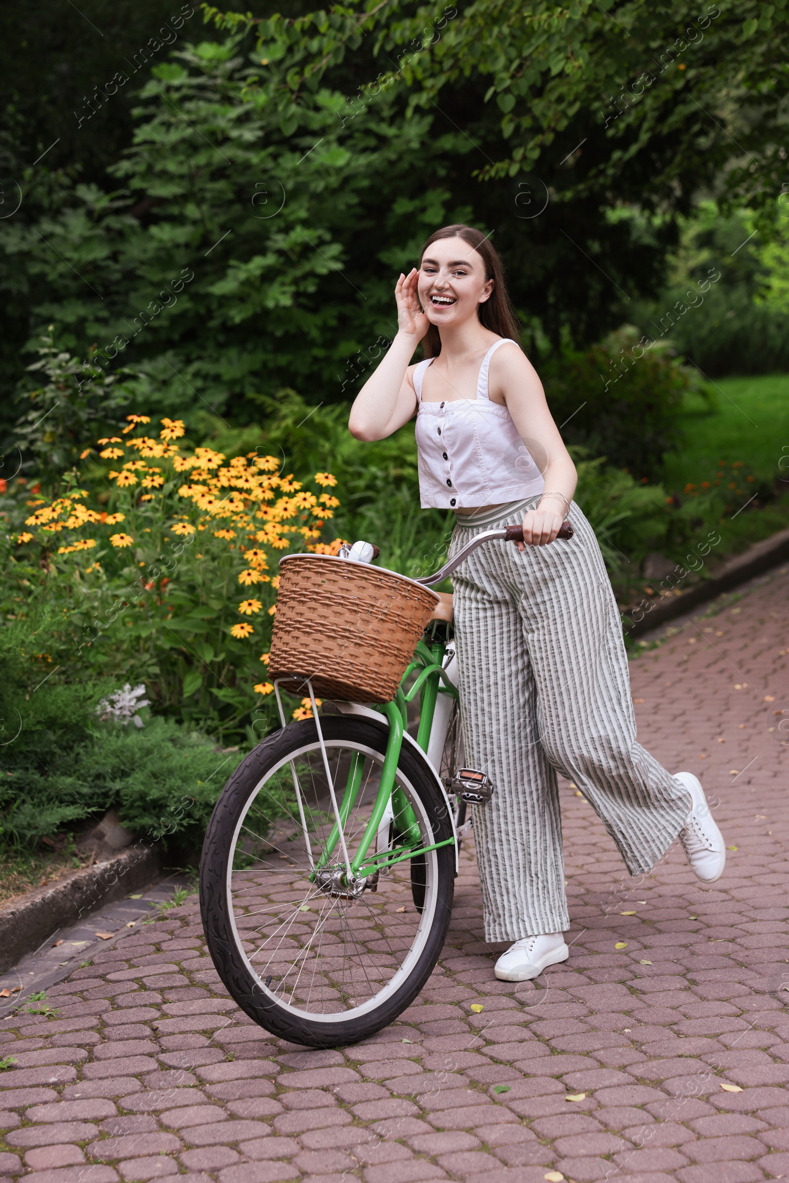 Photo of Happy woman walking her bicycle in park