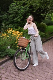 Photo of Happy woman walking her bicycle in park