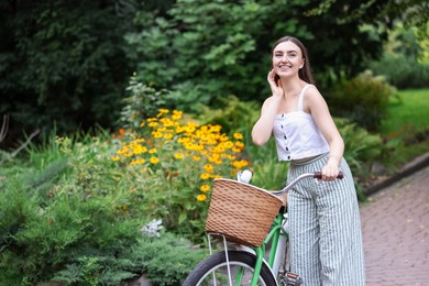 Photo of Happy woman walking bicycle in park. Space for text