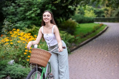 Photo of Happy woman walking bicycle in park. Space for text
