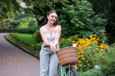 Photo of Happy woman walking her bicycle in park
