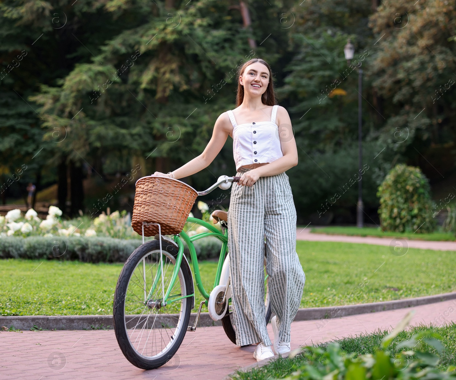 Photo of Happy woman walking her bicycle in park