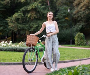 Photo of Happy woman walking her bicycle in park