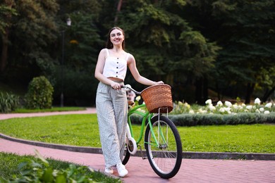 Photo of Happy woman walking her bicycle in park