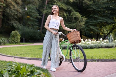Photo of Happy woman walking her bicycle in park
