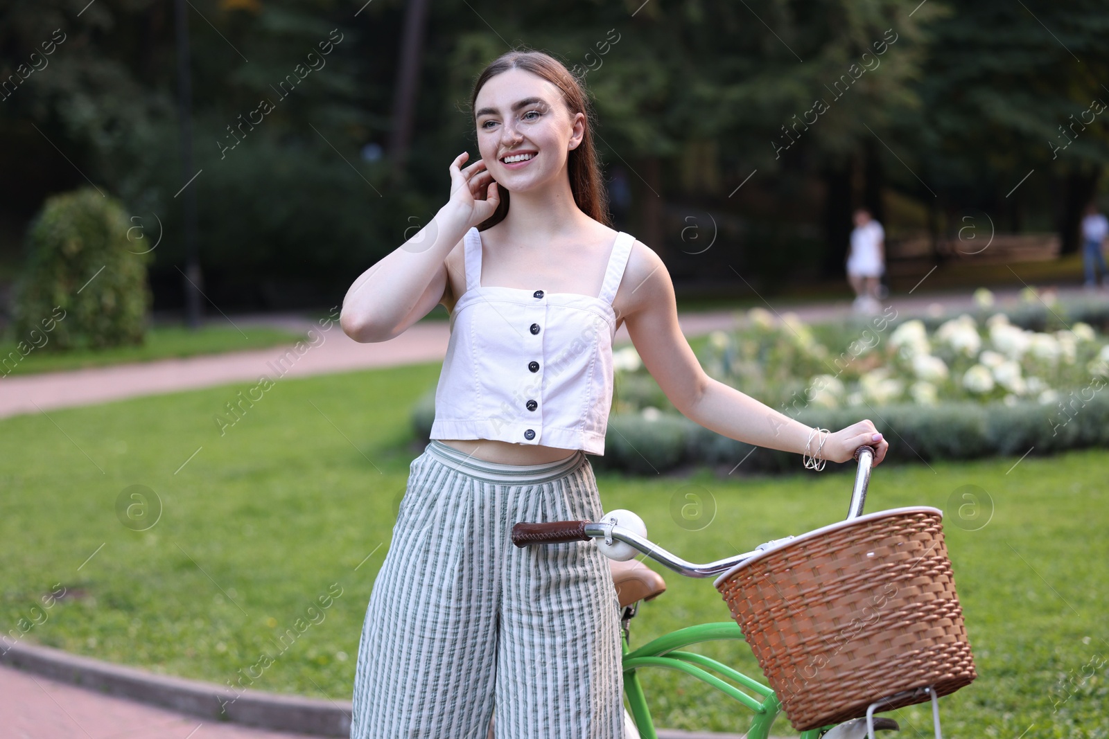 Photo of Happy woman walking her bicycle in park