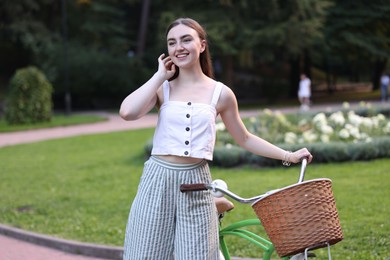 Photo of Happy woman walking her bicycle in park
